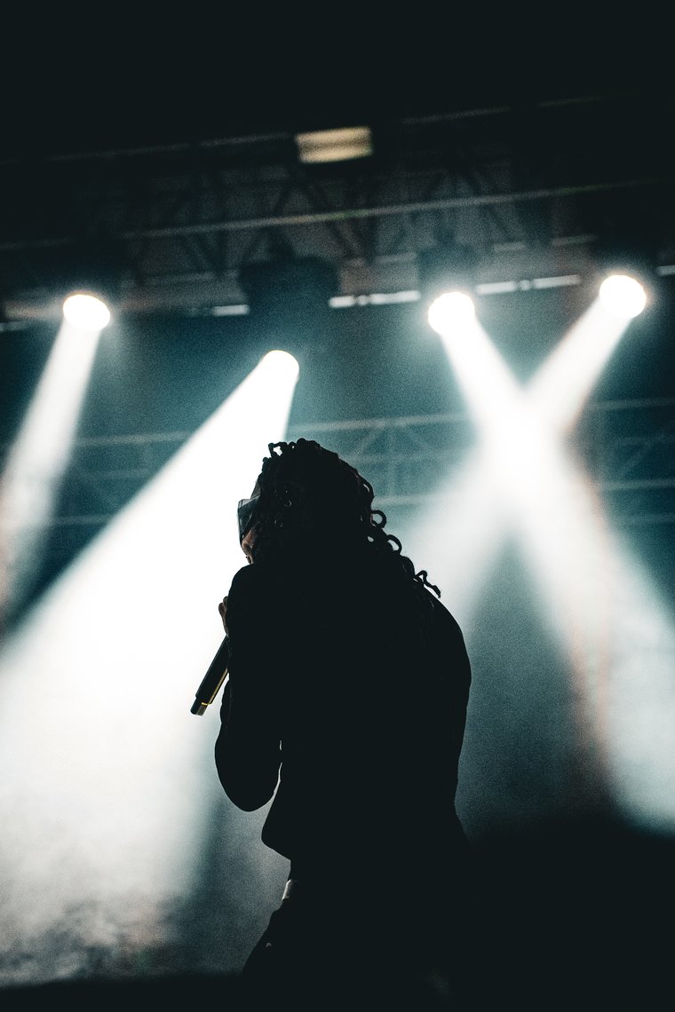 Destroy Lonely silhouetted on stage under crossed spotlights, Middlebury, VT