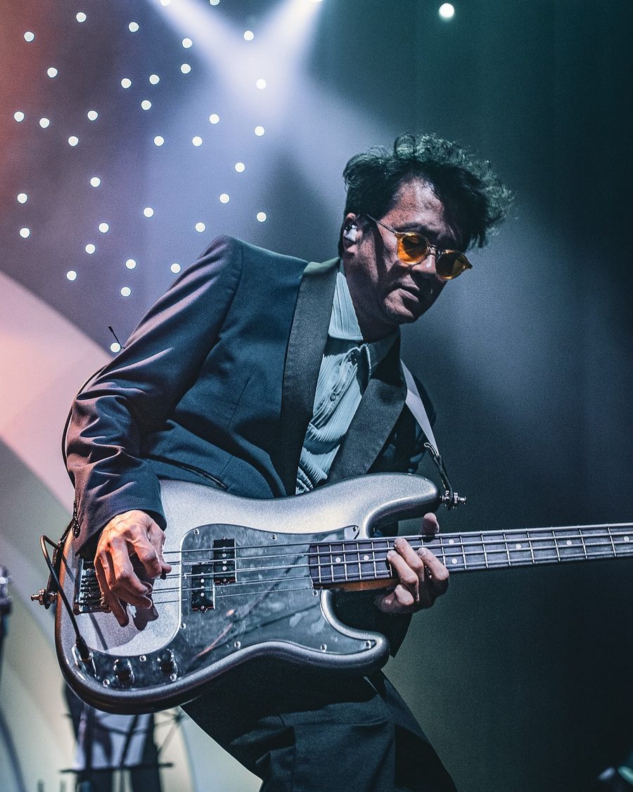 Saint Motel bassist in a dark suit and amber glasses playing a silver bass, Boston, MA